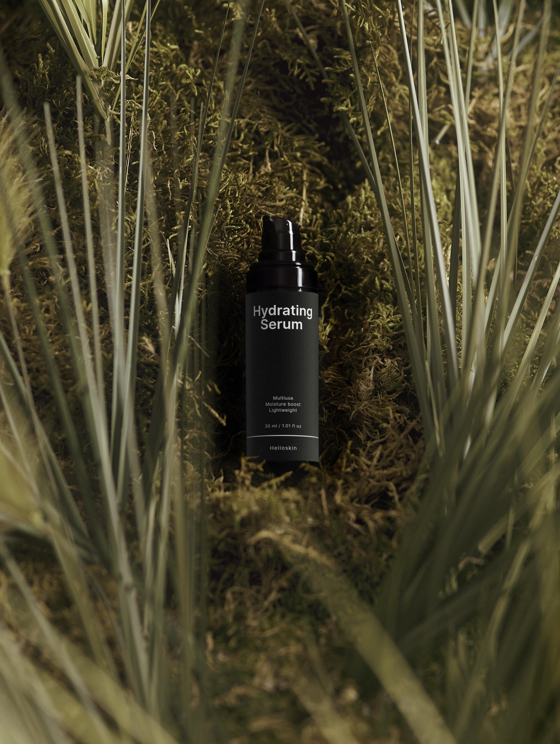 Black serum bottle labeled 'Hydrating Serum' surrounded by grass and plants