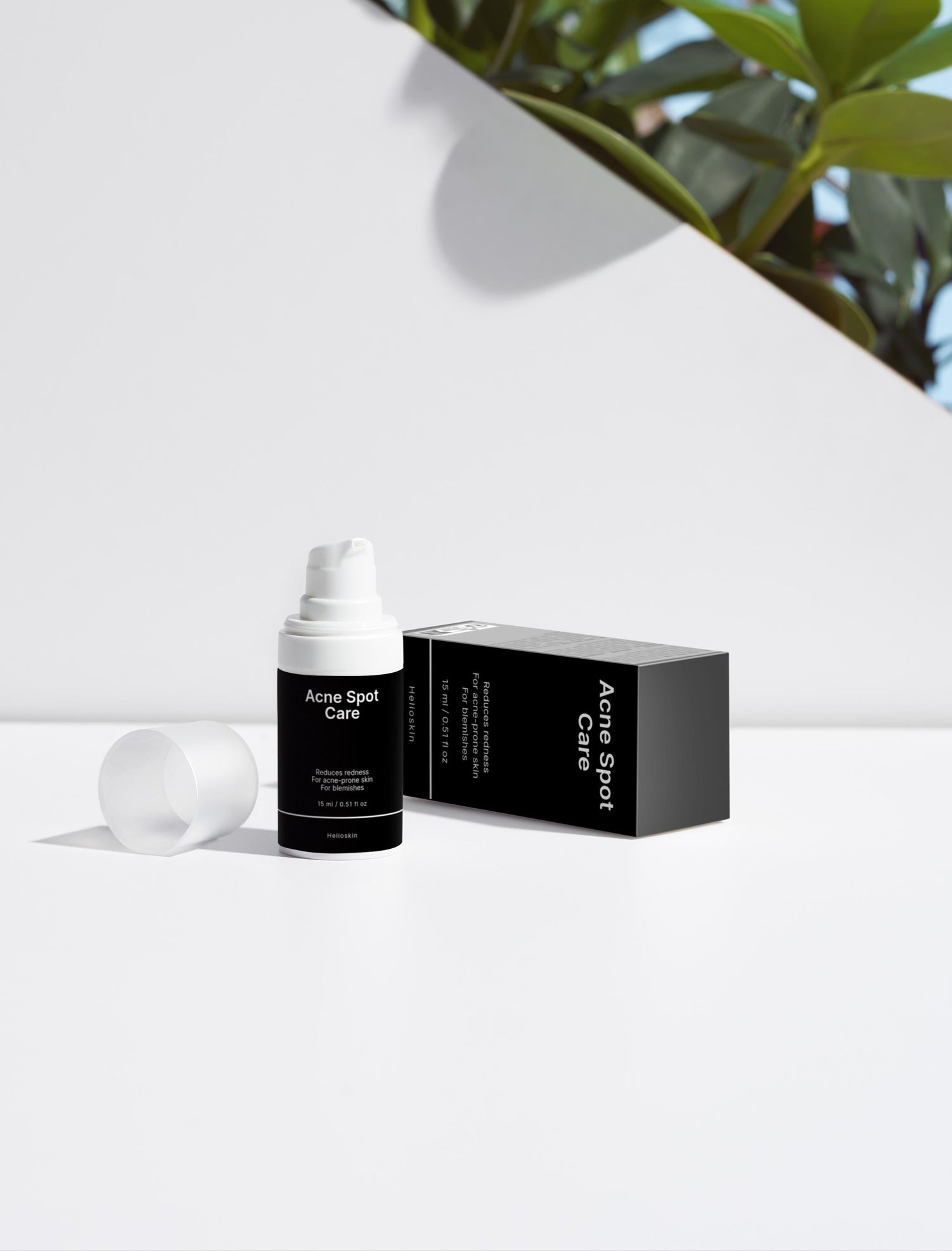 Skincare bottle and packaging on a white background with greenery in the corner