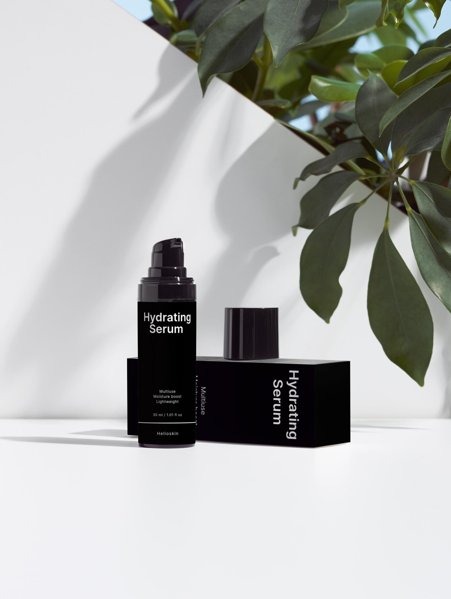 Hydrating Serum bottle and packaging on a white surface with green leaves in the background