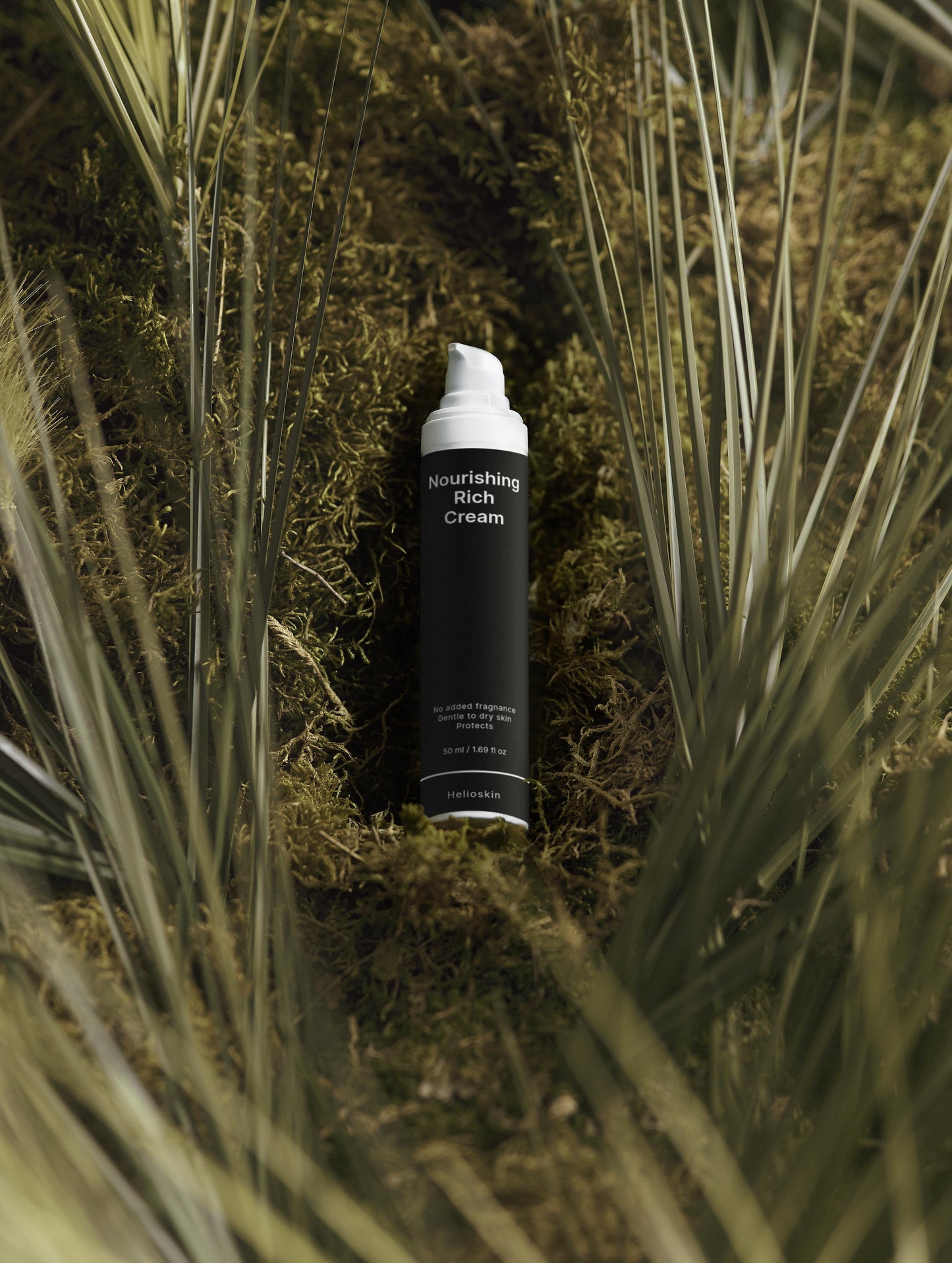 Skincare product bottle labeled 'Nourishing Rich Cream' on a natural background with grass and moss.