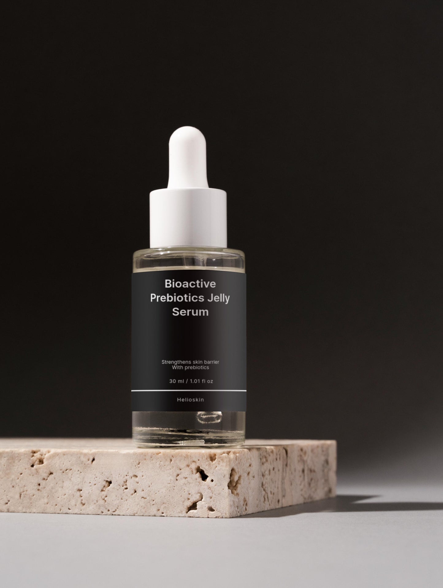 Bioactive Prebiotics Jelly Serum bottle on a stone platform with a black background