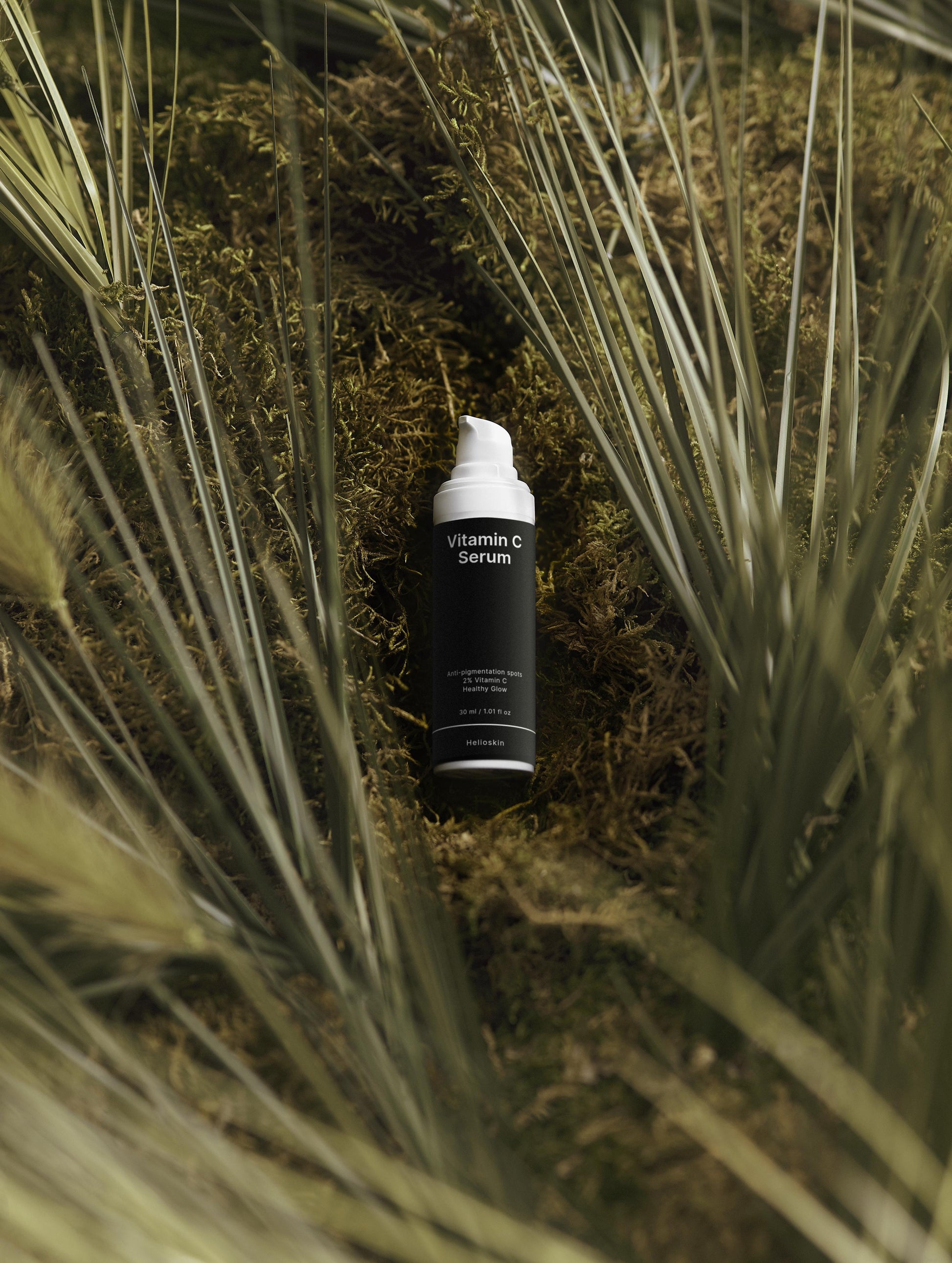Skincare product labeled 'Vitamin C' on a natural background with grass and moss.