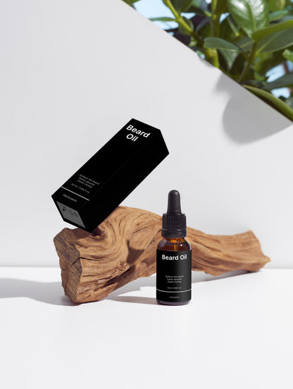 Beard oil bottle and packaging on a white surface with a wooden block and plant in the background