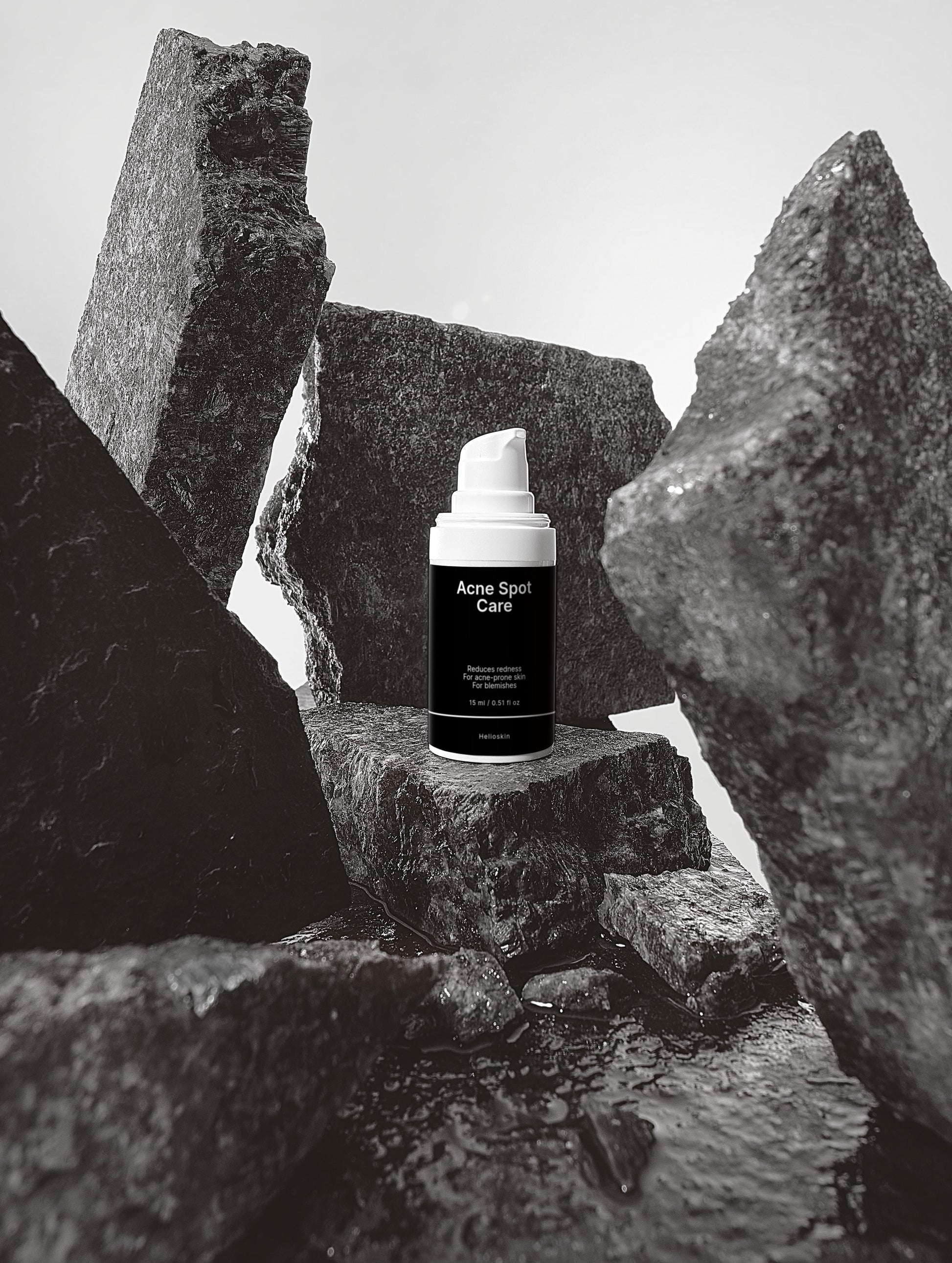 Skincare product labeled 'Acne Spot Care' on a rocky surface